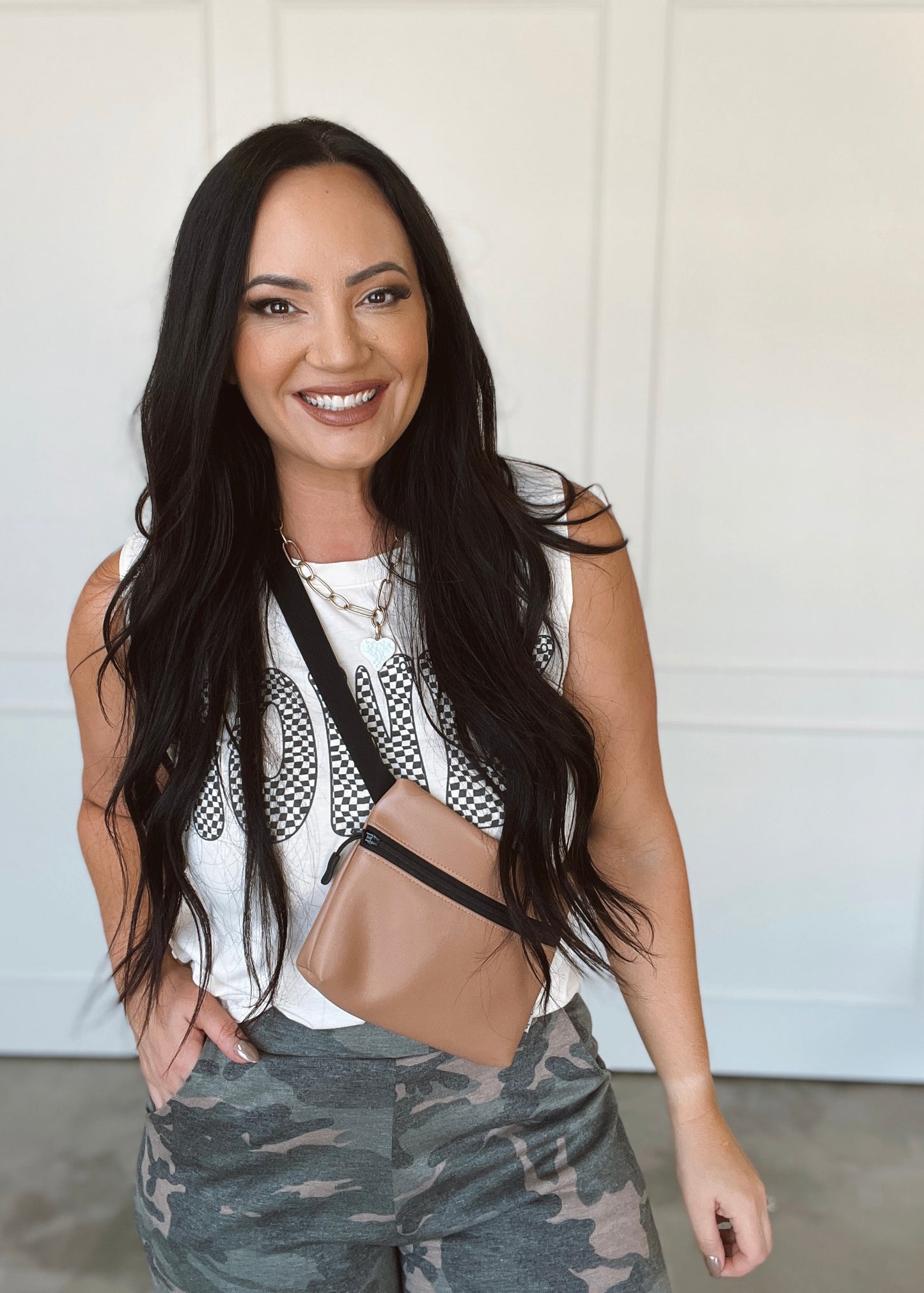 Woman wearing a white top with mesh design and camouflage pants against a white background