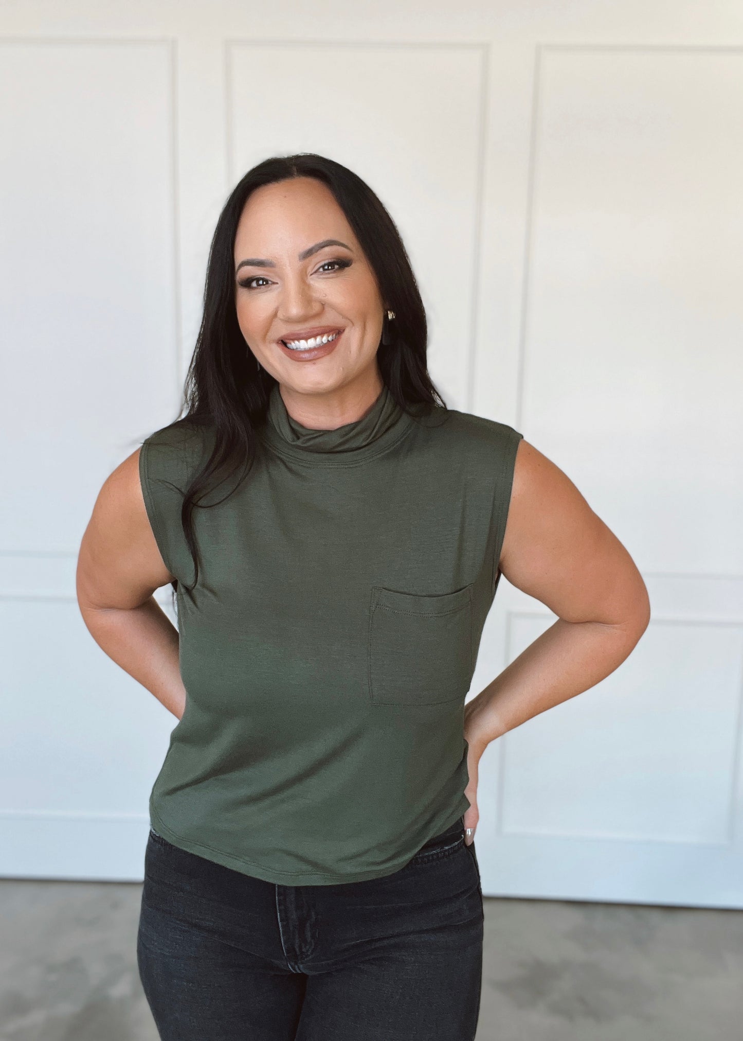 Woman wearing a green sleeveless top with a white background