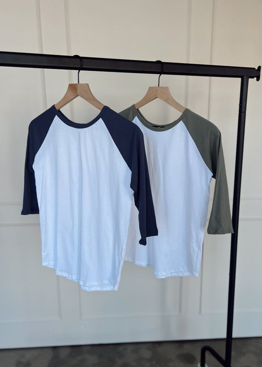 Two baseball shirts on hangers against a white wall