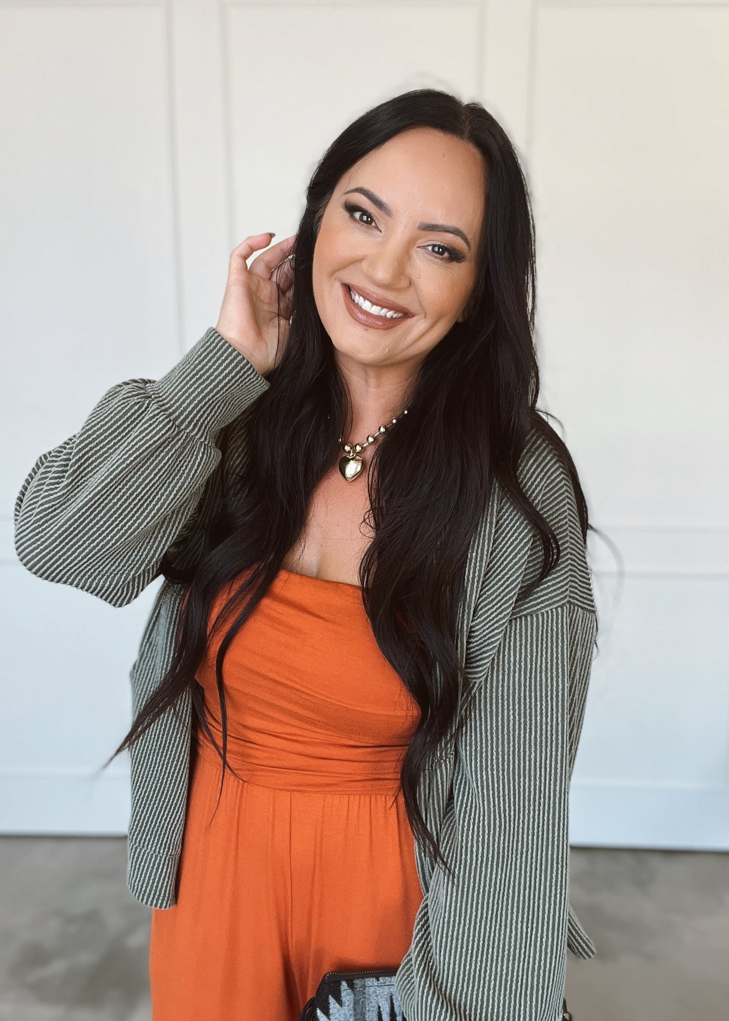 Woman wearing an orange jumper and green blazer indoors