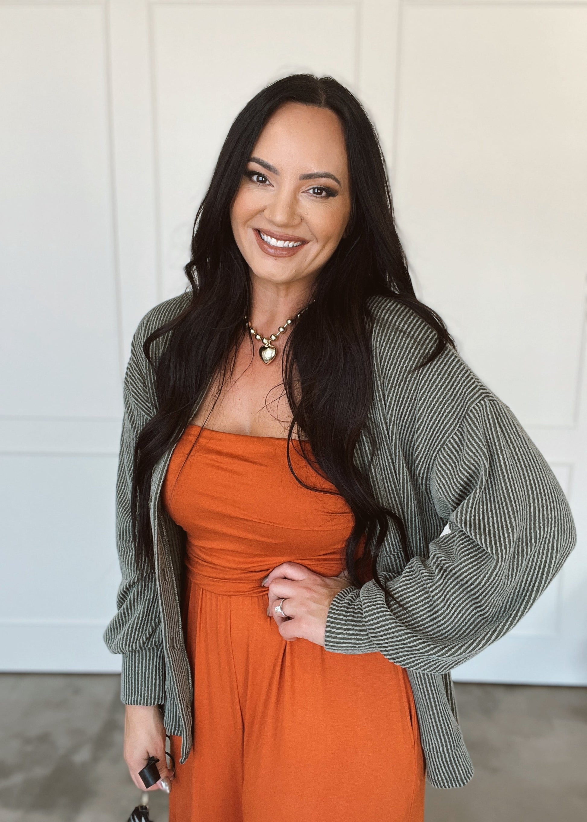 Woman wearing an orange jumper and green cardigan against a white background