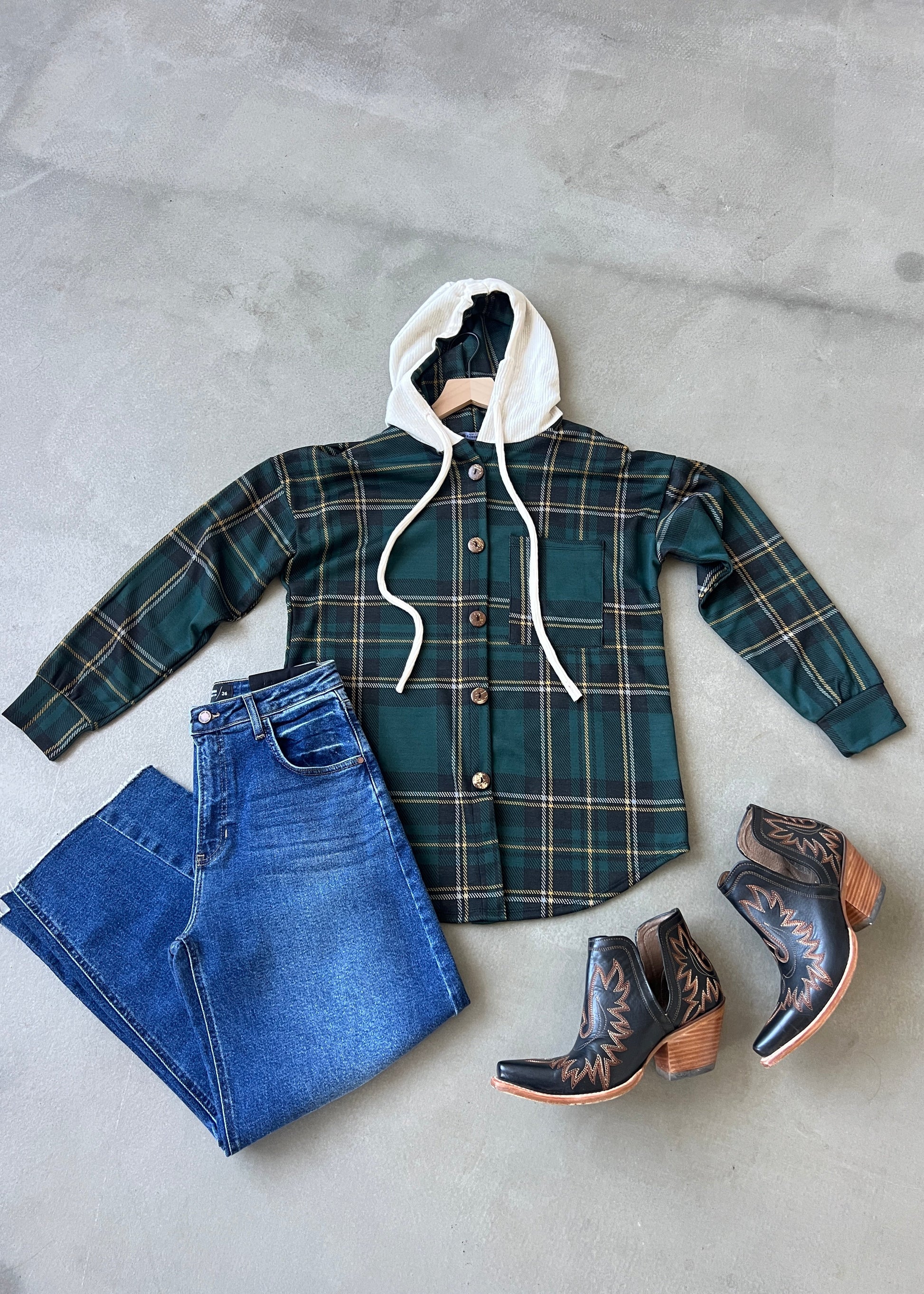 Plaid jacket, jeans, and cowboy boots on a concrete surface