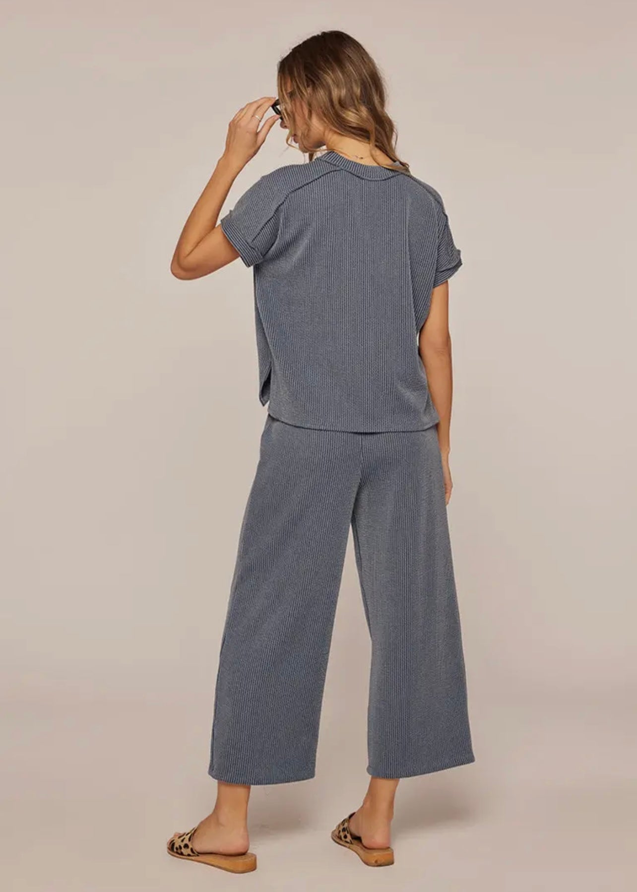 Woman wearing a blue outfit with wide-leg pants on a beige background