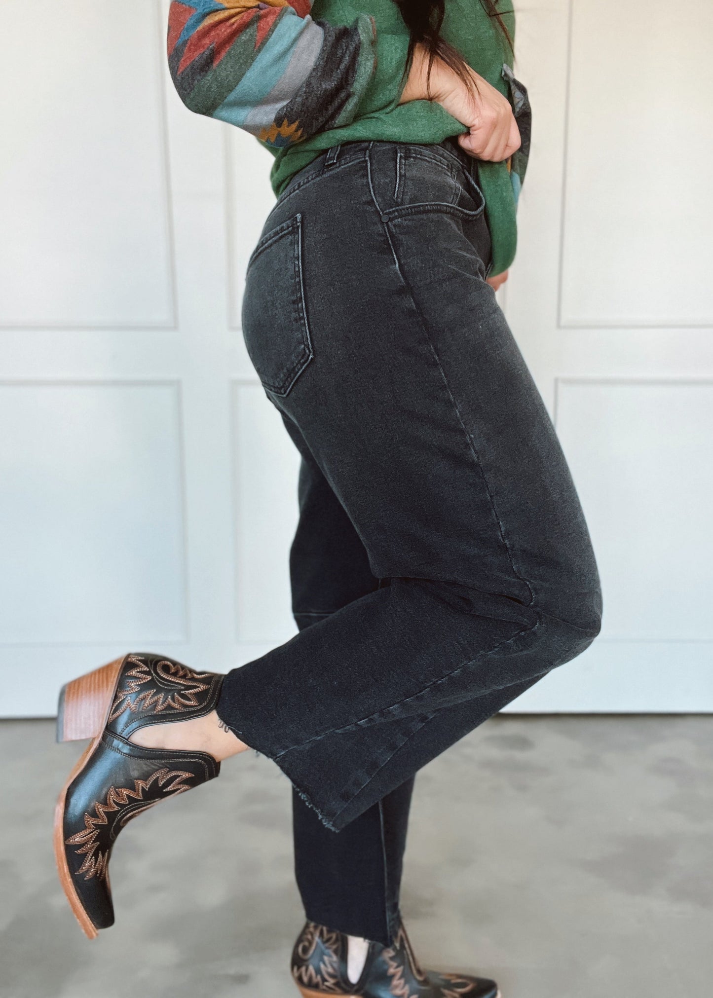 Person wearing black jeans and patterned shoes against a white background