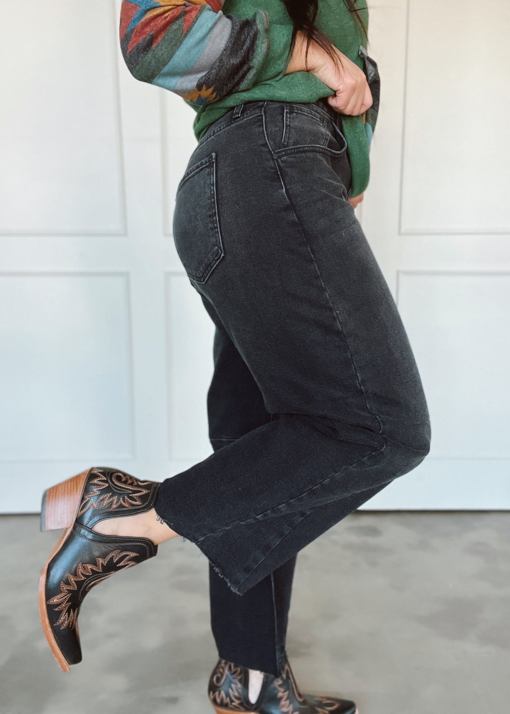 Person wearing black jeans and patterned shoes against a white background