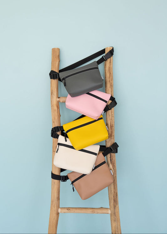 Colorful bags arranged on a wooden ladder against a light blue background